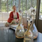 Nancy Reichl Lange est assise devant une table basse avec trois vases en verre pour son entrevue.