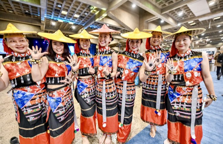 Un groupe de danseurs asiatiques prenant la pose pour une photo lors de leurs voyages.