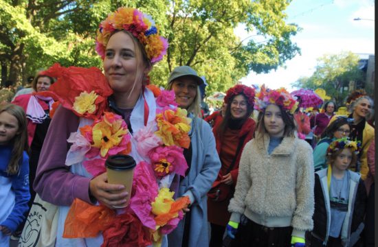 Les festivaliers arborant des couronnes de fleurs se promènent dans une rue, créant un phénomène vibrant.