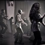 Une photo en noir et blanc d'une soirée disco mettant en vedette un groupe de personnes sur scène.