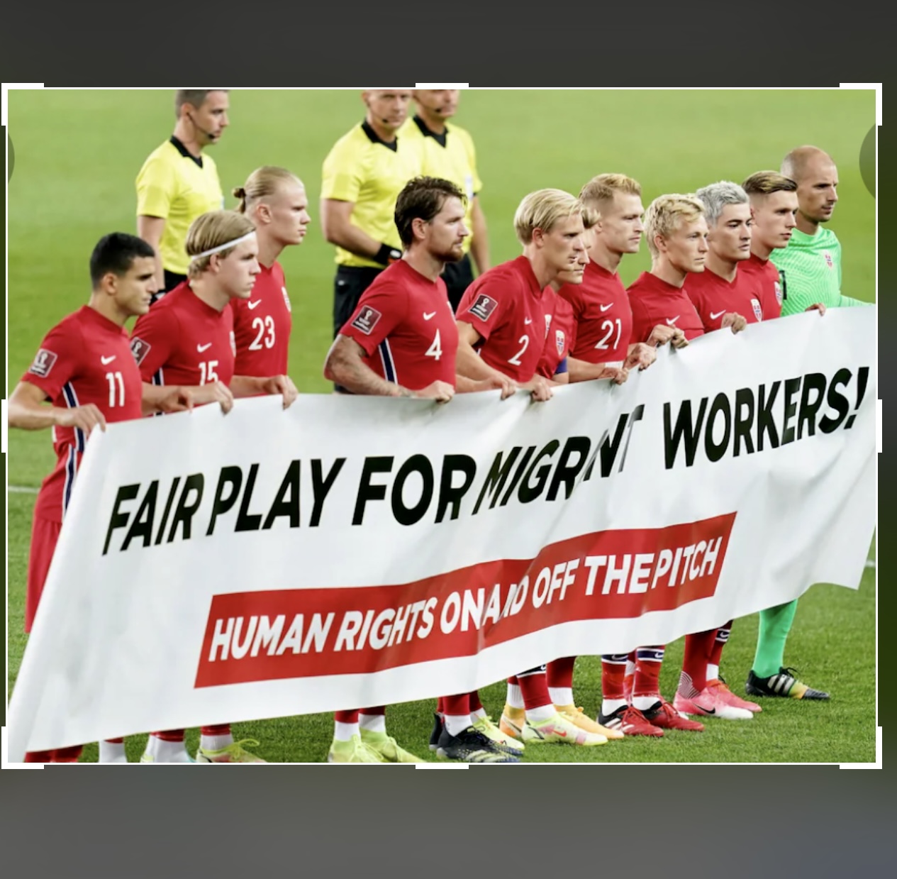 Un groupe de joueurs de football tient une banderole qui dit fair-play pour les travailleurs migrants.