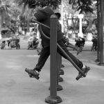 Photo en noir et blanc d’un homme faisant des pompes sur des poteaux au Cambodge.