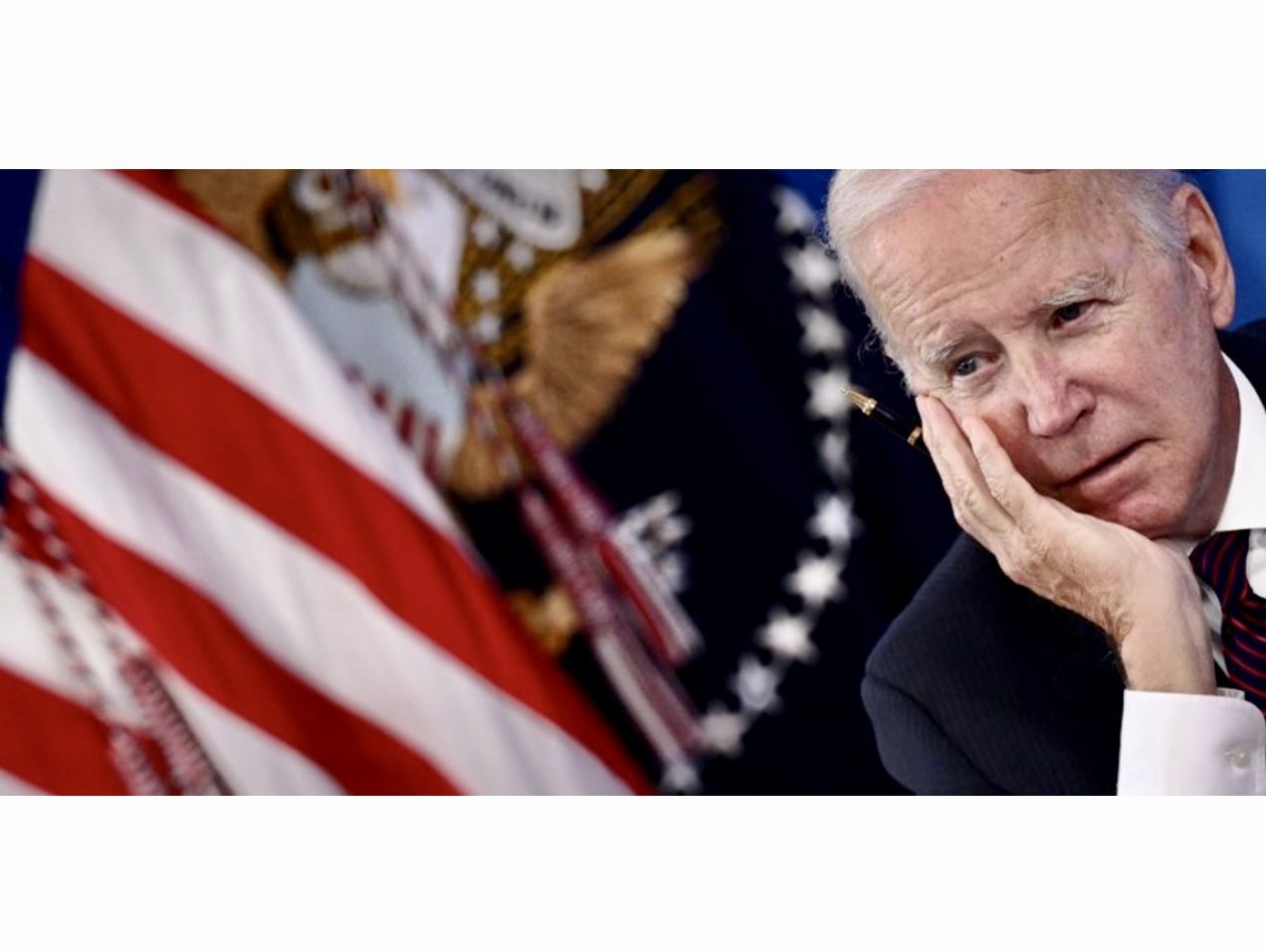 Joe Biden, figure de la politique américaine, est assis devant un drapeau américain.