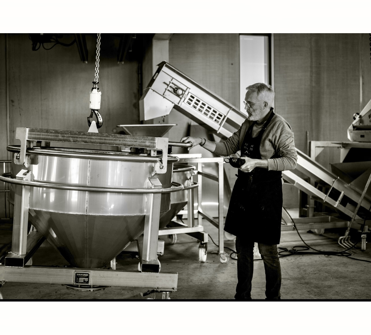 Photo en noir et blanc d'un homme debout dans une usine produisant du Vin français.