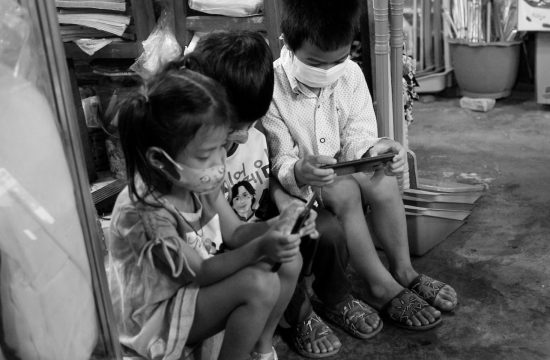 Trois enfants assistent devant un magasin avec des masques, photos du Cambodge.