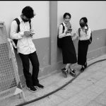 Un groupe de personnes debout près d’un mur, prenant de belles photos du Cambodge avec leur téléphone portable.