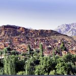 Les Grands Explorateurs découvrent un village de montagne pittoresque en Iran entouré d'arbres luxuriants et de montagnes majestueuses.