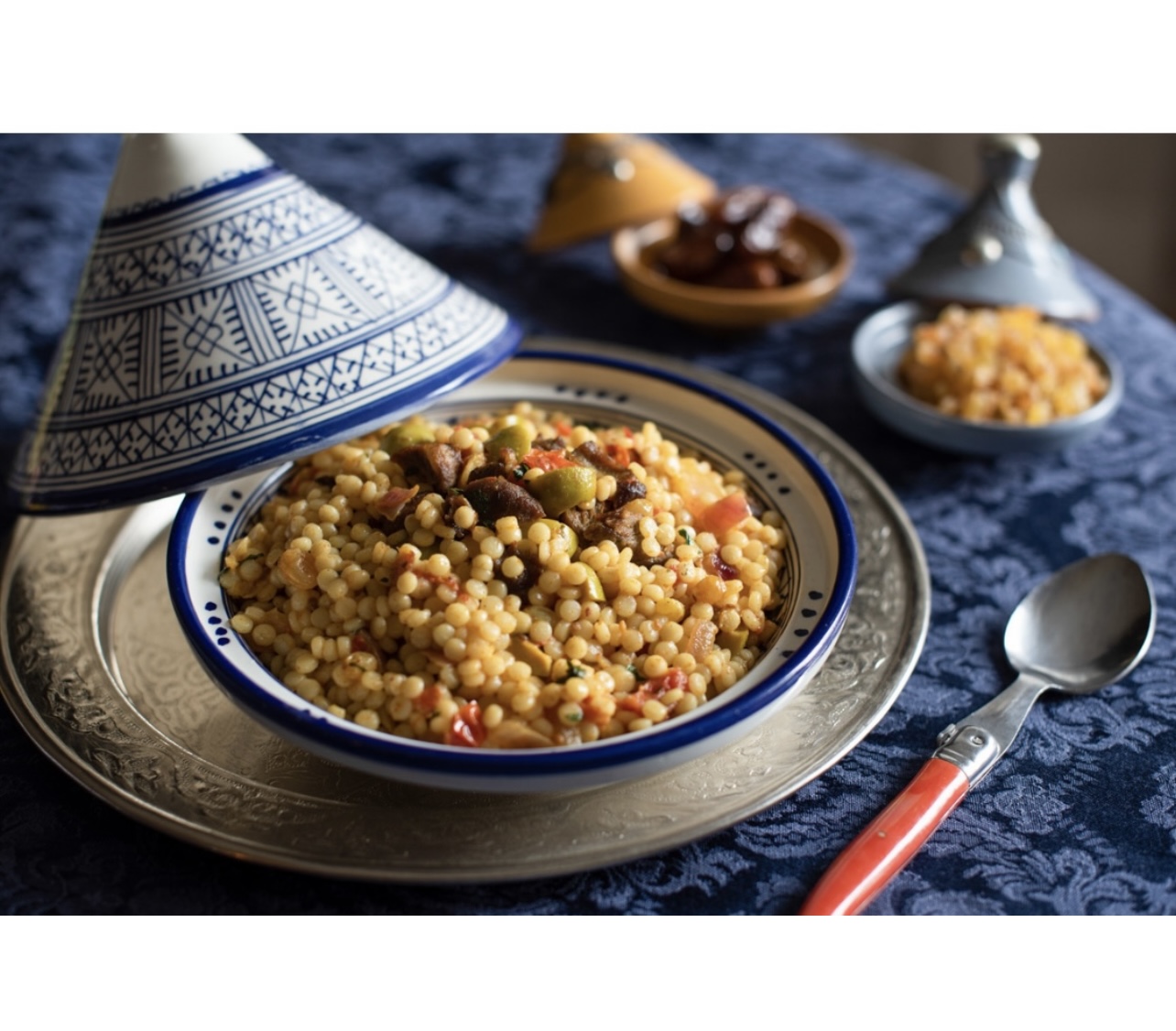 Couscous marocain aux dattes et olives dans un bol sur une table.