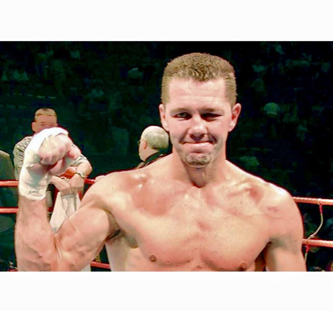 Un boxeur pose triomphalement, le poing en l’air.