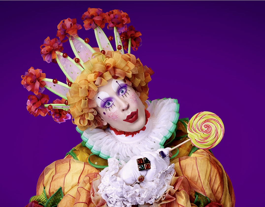 Un clown de ballet en costume tenant une sucette.