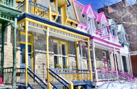 Une rangée de maisons peintes en couleurs au Canada, couvertes de neige.