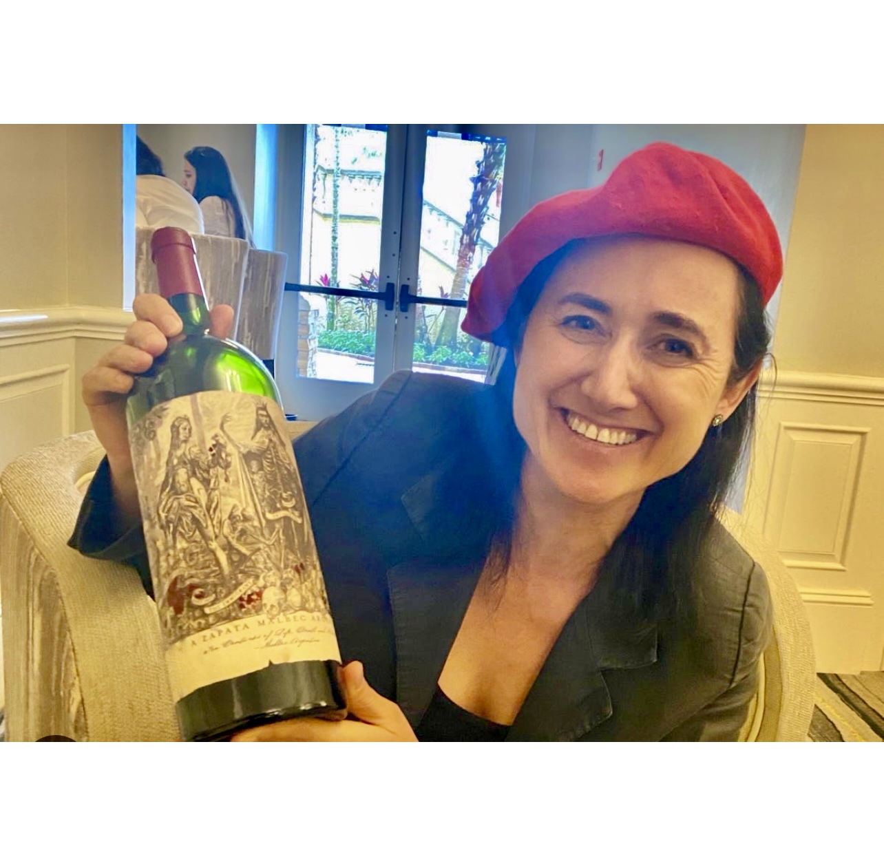 Une femme tenant une bouteille de vin avec un béret rouge dessus, célébrant les Vins de la semaine.