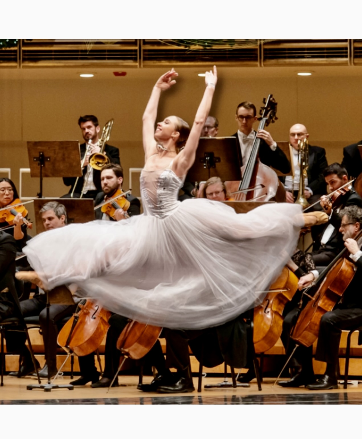 Une danseuse de ballet en robe blanche exécutant avec grâce les mélodies envoûtantes de la musique viennoise, ornée par un orchestre.