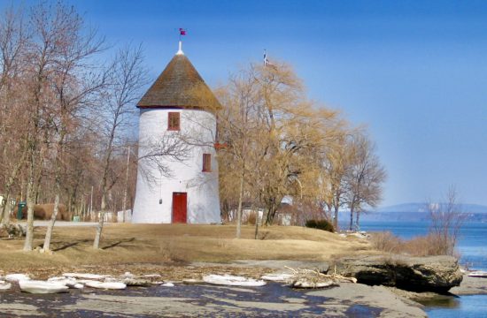 Un phare blanc et rouge au bord d'un plan d'eau dans les Villages du Québec.