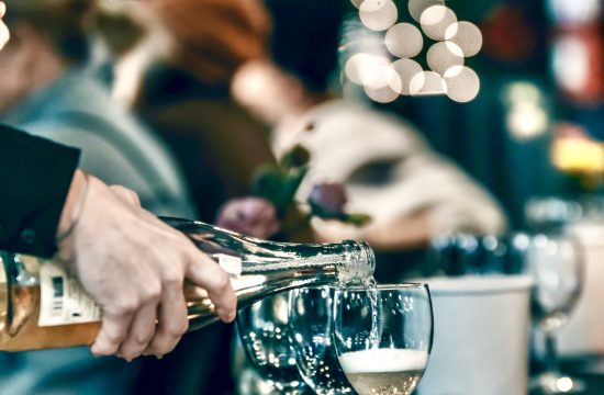 Une personne versant des Vins d'Alsace dans des verres à une table.