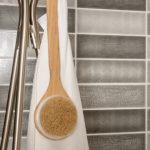 Une brosse en bois avec une serviette accrochée au mur à côté d'un mur carrelé dans un Aménagement de la cuisine.