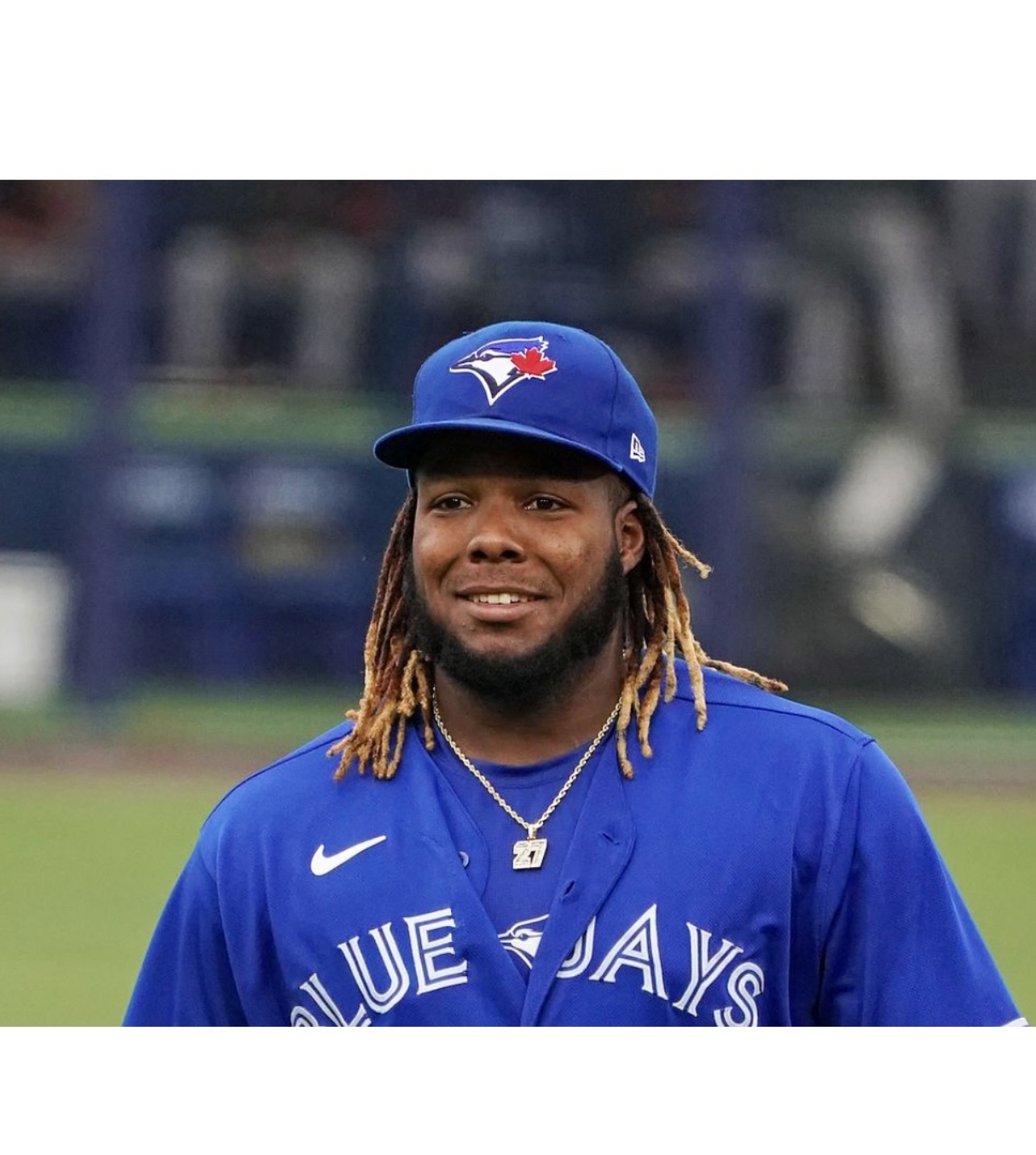 Un joueur de baseball des Blue Jays de Toronto avec des dreadlocks sourit sur le terrain.