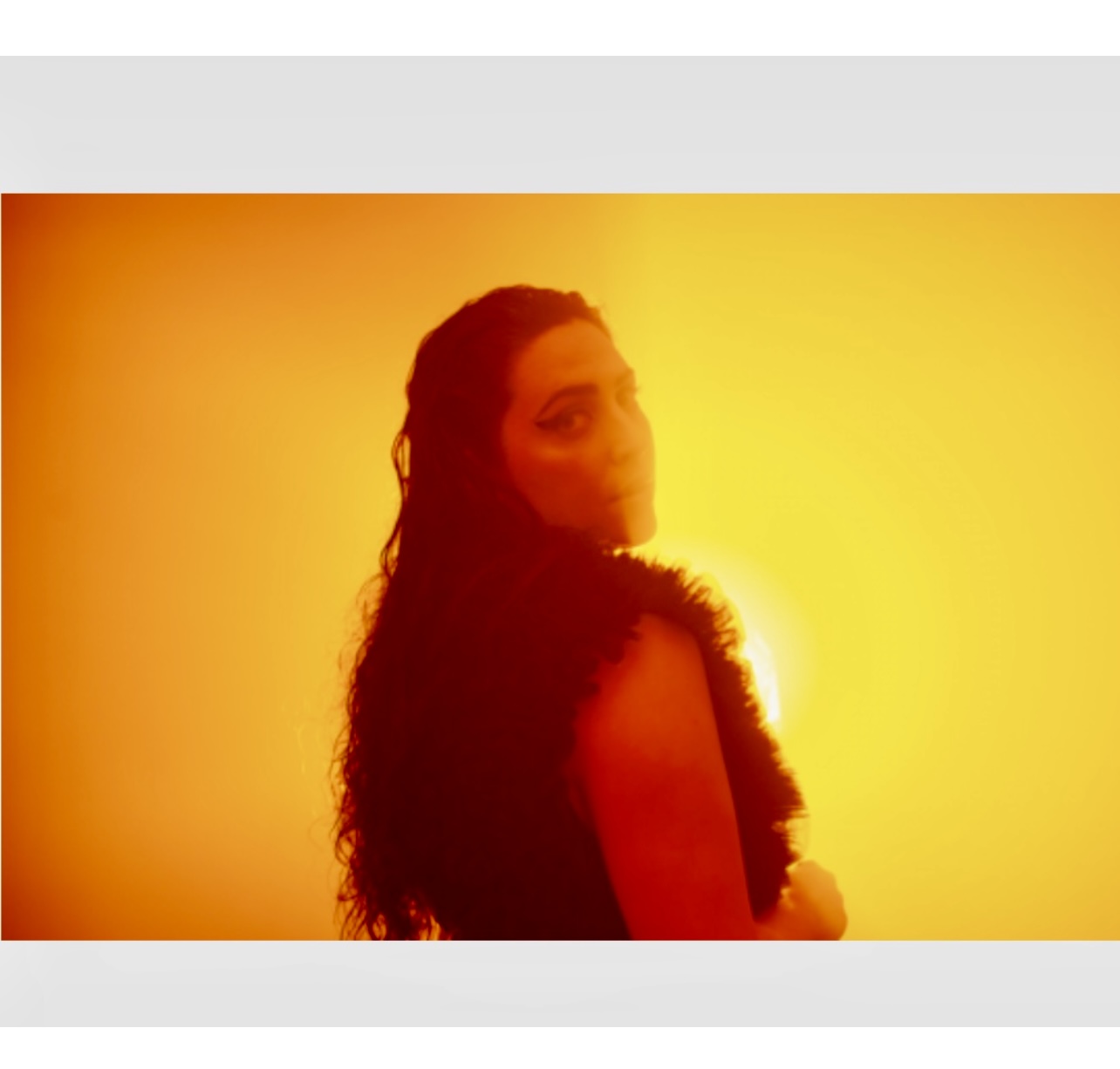 Une femme aux cheveux longs debout devant une lumière orange, dans le cadre d'une séance photo de Musique québécoise.