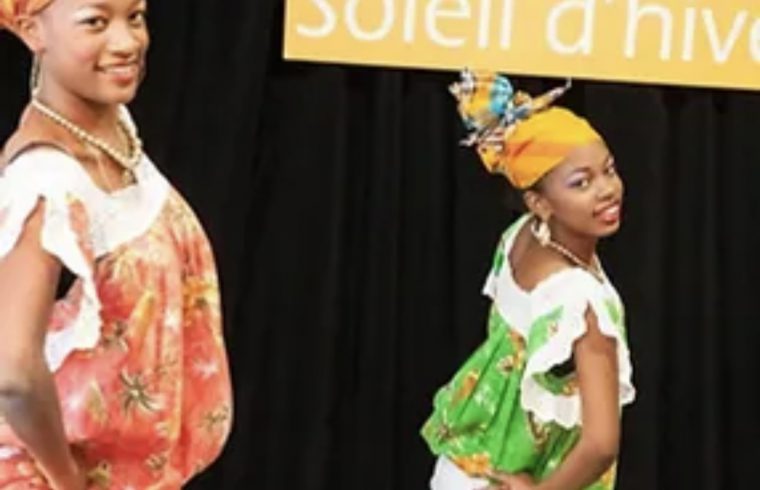 Description : Deux femmes africaines vêtues de vêtements colorés se tiennent devant une pancarte annonçant Vogages Soleil.