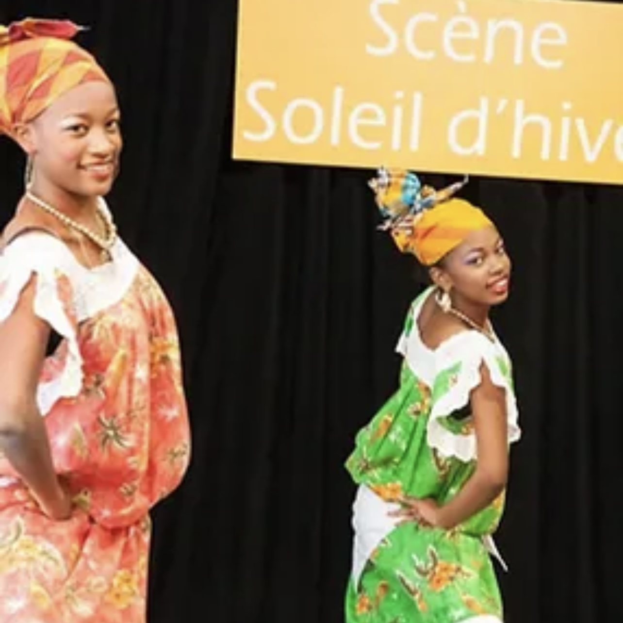 Description : Deux femmes africaines vêtues de vêtements colorés se tiennent devant une pancarte annonçant Vogages Soleil.
