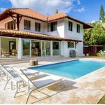 Une maison blanche avec une piscine et des chaises longues à la Casa de Campo en République Dominicaine.