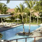 Une Casa de Campo en République Dominicaine avec une piscine entourée de palmiers et de chaises longues.