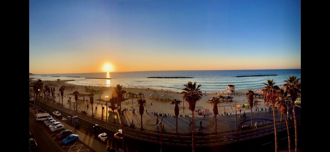 Le soleil se couche sur une plage bordée de palmiers en Israël.