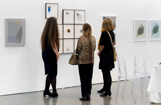 Trois femmes examinant les œuvres d'art exposées dans une galerie d'art.