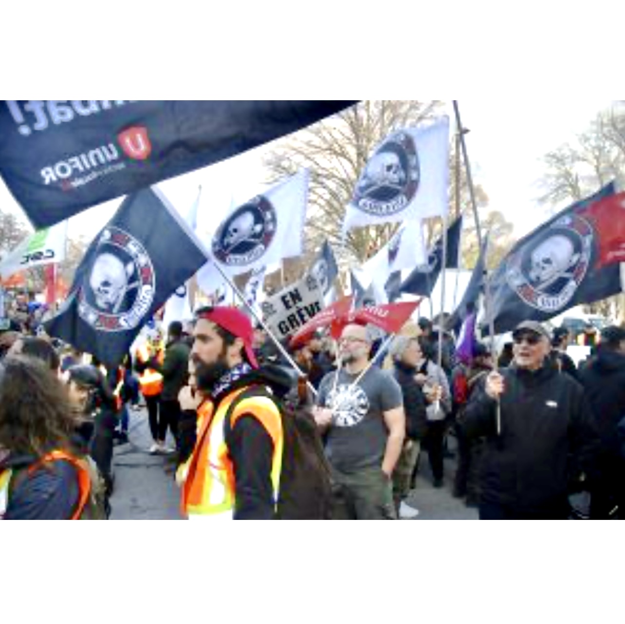 Une procession des Marches avec des participants tenant des drapeaux et des banderoles.