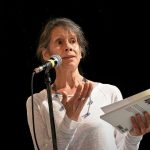 Une femme, lauréate du Prix de la poésie 2023, tenant un livre et parlant dans un micro.