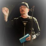 Un homme en veste noire s'exprime dans un micro lors du Prix de la poésie 2023.
