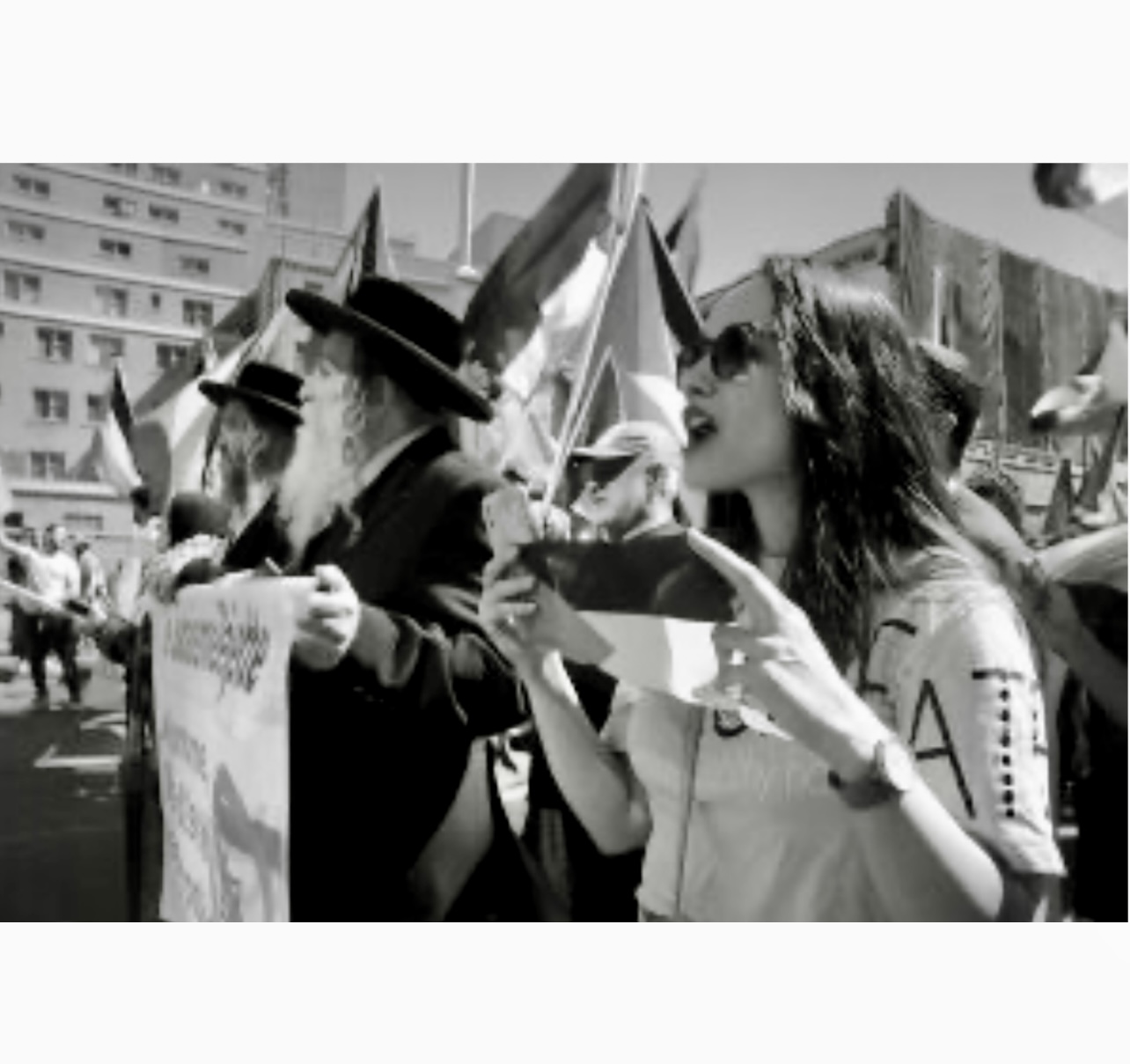 Un groupe de personnes brandissant des pancartes lors d’une Marche pro-palestinienne, capturé sur une photo en noir et blanc.