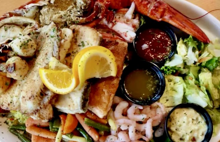 Une assiette avec du homard, des crevettes et des légumes. Inspiré de la route gourmande de la Côte-Nord.