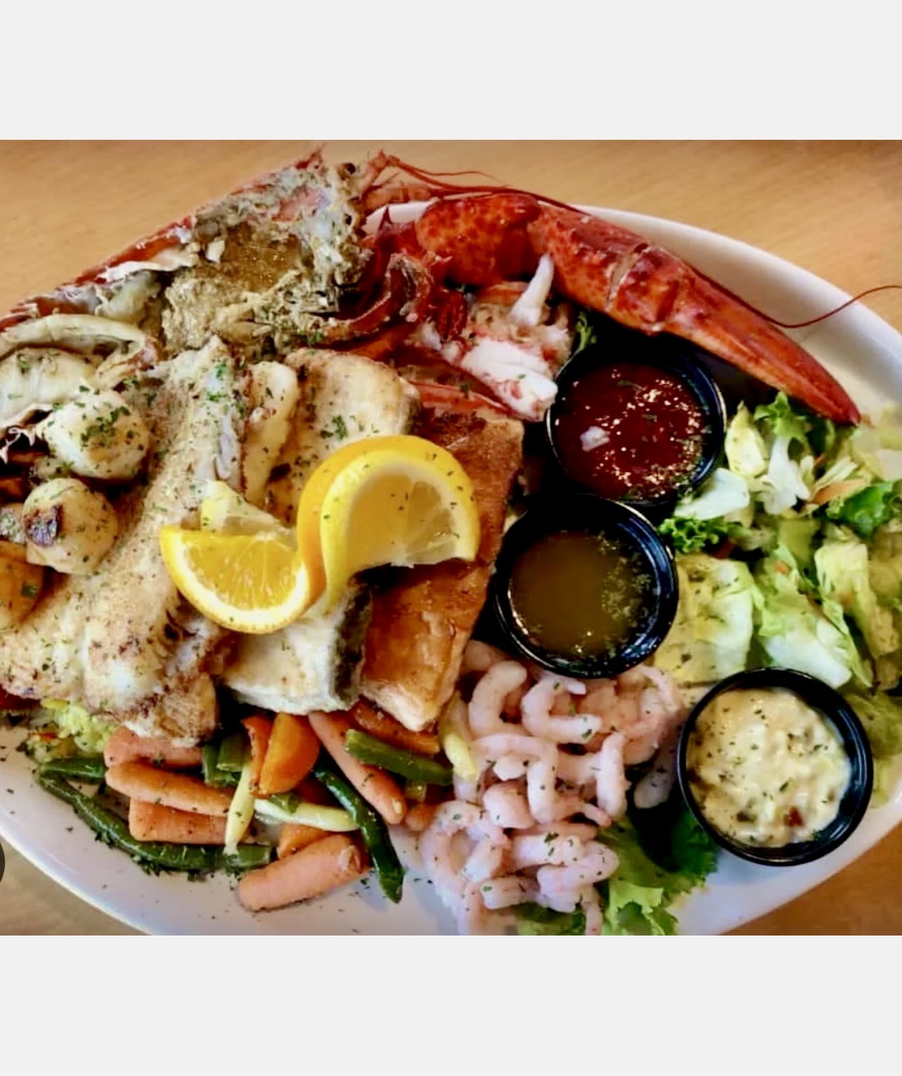 Une assiette avec du homard, des crevettes et des légumes. Inspiré de la route gourmande de la Côte-Nord.