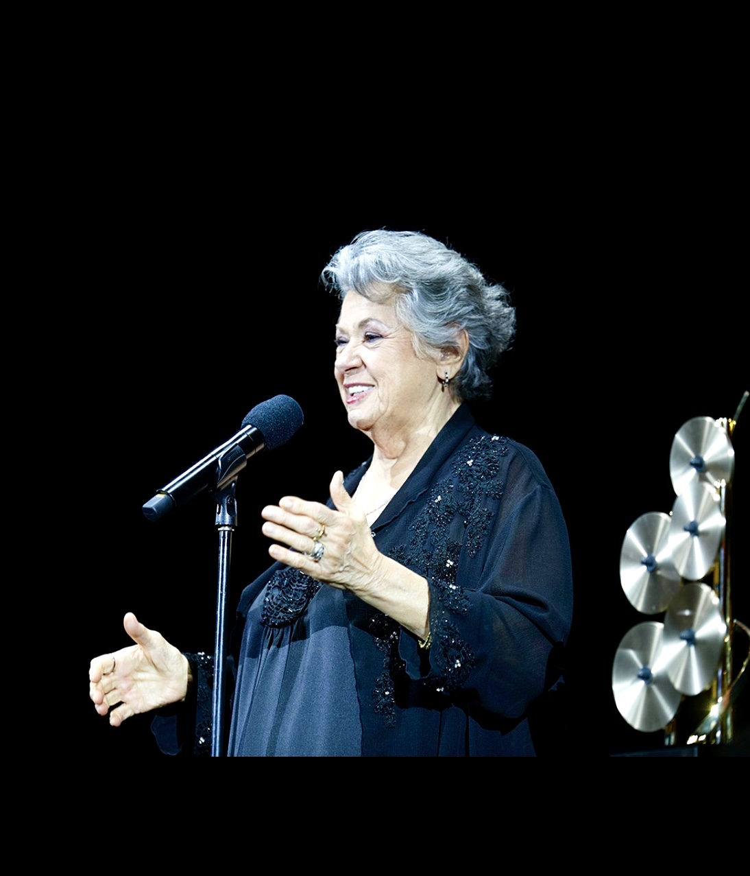 Une femme âgée en prestation au 33e gala annuel de la SOCAN, chantant dans un microphone.