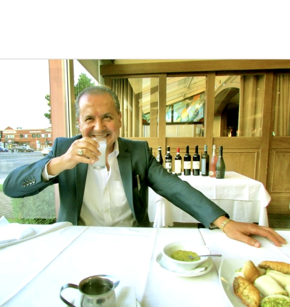 Un homme en costume savourant les saveurs de la cuisine libanaise assis à une table.