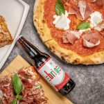 Zapoli, une étape incontournable, avec deux pizzas et une bouteille de bière sur une table.
