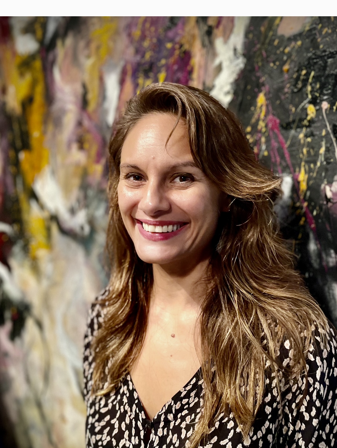 Une femme souriante devant un tableau abstrait de Sorensen.