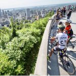 Un groupe de personnes faisant du vélo sur une colline surplombant une ville, profitant d'une Escale à Montréal avec Ulysse.