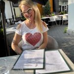 Une femme assise à une table extérieure portant un t-shirt en forme de cœur.