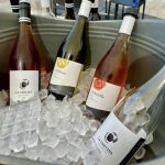 Le vignoble Rivière du Chêne, 25 ans de réussite, propose une collection de quatre bouteilles de vin refroidies dans un seau avec de la glace.