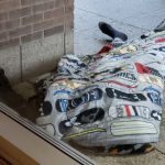 Un sans-abri doré dans une couverture devant un bâtiment.