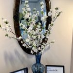 La Maison de l'Île, un vase de fleurs sur un bureau avec miroir.