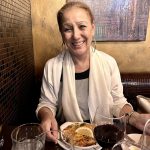Une femme appréciant le charme du Luciano Ristorante à une table avec une assiette de plats et de vins.