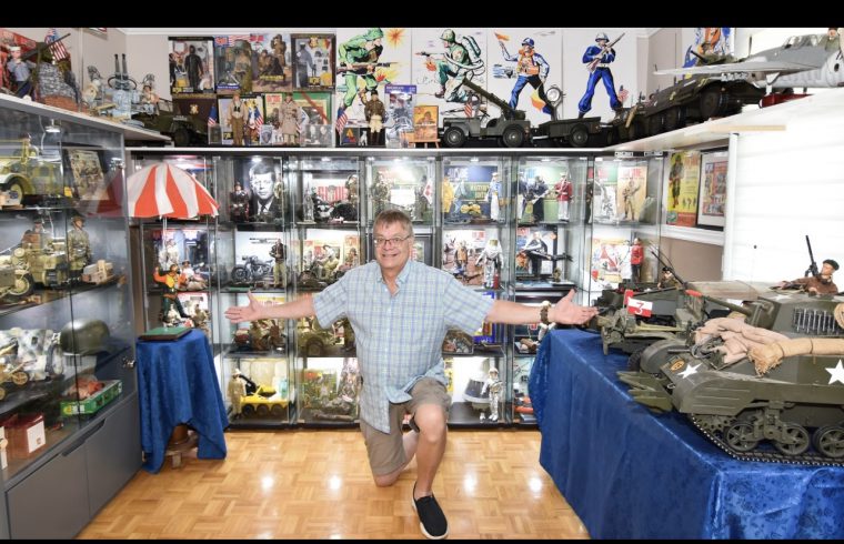 Un homme vivant posant devant une exposition de chars jouets portant des vêtements G.I. La tenue de Joe.