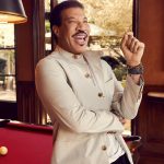 Lionel Richie, un homme vêtu d'une veste beige, debout à côté d'une table de billard.