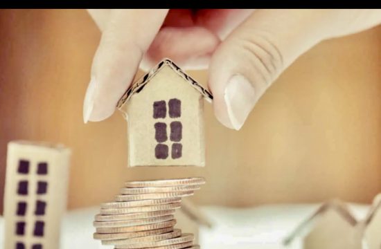 Un courtier hypothécaire, dans son rôle important et utile, tient une pile de pièces de monnaie avec une maison au sommet.