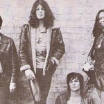 Un groupe de personnes posant devant un mur de briques avec une ambiance rock star