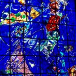 Un vitrail bleu représentant le Coeur de Nice de Chagall dans une église.