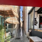 Une ruelle étroite avec tables et parasols devant un restaurant, qui dégage une douceur de vivre cassisienne.